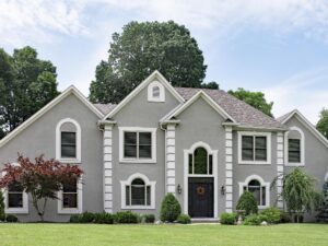 Two-story gray home with white decorative trim and black front entry door
